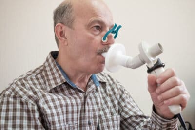 Man taking a lung function test by exhaling into a tube.